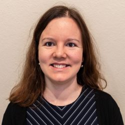 Photo of Soizic smiling at the camera. She's wearing a navy patterned top.