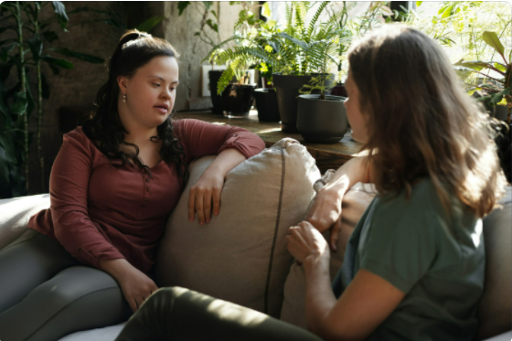 Two women in conversation sitting on a couch.