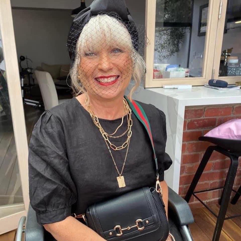 Nadine McMaster. A photo of a person smiling with grey coloured hair and wearing a black top