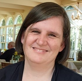 Shelley Spencer. Close up headshot of a person smiling with brown hair.