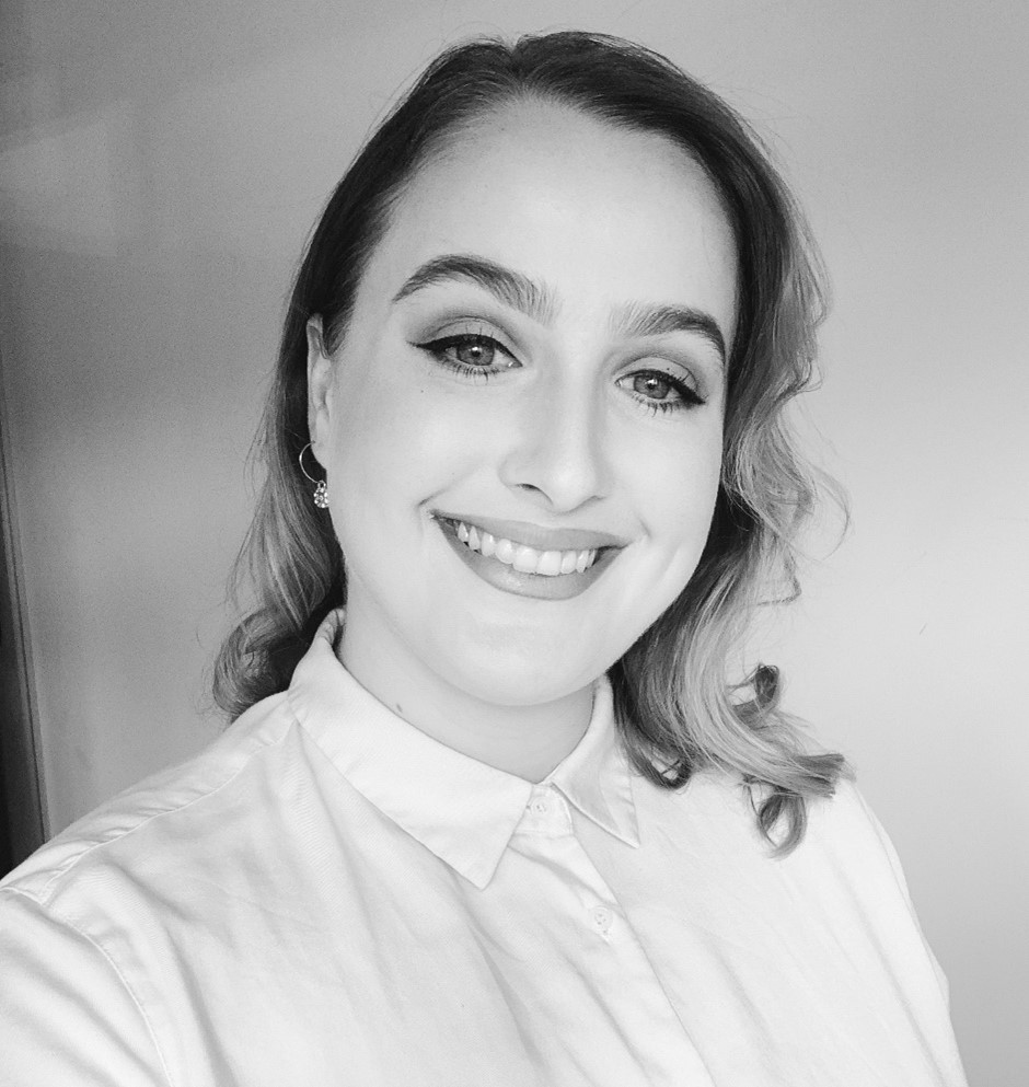 A black and white image of a smiling white woman in a pale collared shirt with medium-length hair.